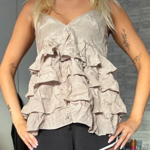 Beige volangig linnetopp med v-ringning - Supersöt beige linnetopp med flera lager volanger och v-ringad hals. 