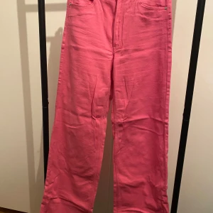 Rosa raka jeans från H&M, strl 38 - Snygga rosa jeans från H&M i storlek 38. Byxorna har raka ben, klassisk femficksdesign och är tillverkade i bomull. Perfekta för dig som vill sticka ut med färg och ändå ha en enkel, clean look.