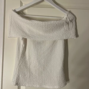 Vit offshoulder topp från h&m  - Prislapp kvar helt oanvänd! Supersöt vit offshoulder topp från h&m i smockat tyg. Toppen har en bred volangkant upptill och är ärmlös med axelbandslös design. Perfekt för varma dagar och ger en chill vibe till din outfit.