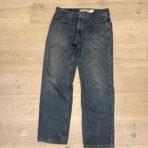 Levi's 550 - Klassiska Levi's 550 jeans i blå denim med rak passform. Jeansen har normal midja och subtila slitningar för en avslappnad look. W32 L30