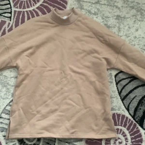 Beige tröja från Frilivin - Säljer en beige polotröja från Frilivin i storlek M. Tröjan har en hög krage och är långärmad med en loose passform. Materialet är mjukt och känns som bomull eller polyester, perfekt för dig som gillar enkel och clean stil.