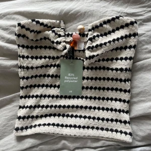 Randig tubtopp från H&M Divided - Säljer en snygg tubtopp från H&M Divided i storlek XS. Toppen är randig i svart och vit, har en bandeauform och är tillverkad av 83% återvunnen polyester. Perfekt för att skapa en cool och trendig look i sommar. Aldrig använd med prislapp kvar, säljer pga den ej passar