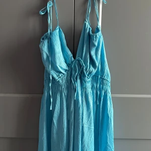 Ljusblå långklänning från H&M - Skickar iväg samma dag eller dagen efter🙌🏼Säljer en ljusblå långklänning från H&M i storlek XL. Klänningen har tunna axelband med knyt, v-ringad urringning och smockad midja. Tillverkad av 99% återvunnen polyester med en lätt, skrynklig textur. Perfekt för sommarens alla tillfällen!