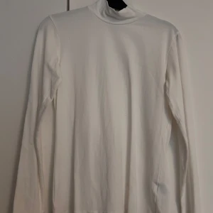 Vit polotröja - Vit polotröja med lång ärm och halv hög hals. Använd under kavaj vid ett tillfälle.
