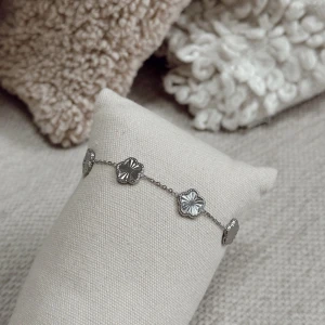Silverarmband med blommor - Snyggt och stilrent armband i silverfärg med små blommor som har en glansig, detaljerad yta. Kedjan är tunn och smidig, och blommorna är jämnt placerade längs armbandet för en elegant look. Perfekt för dig som gillar diskreta men unika smycken.