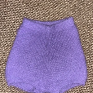 Lila stickade shorts med fluffig känsla - Supermjuka och fluffiga lila shorts i stickat material. De är högmidjade och har en tight passform med ribbad midja. Perfekta för dig som vill ha något unikt och mysigt i garderoben. Färgen är en snygg ljuslila ton som verkligen sticker ut.