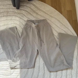 Beige mjukisbyxor från Madlady XS - Säljer ett par beige mjukisbyxor från Madlady x Ilacarlsson i storlek XS. Byxorna har bred resår i midjan, snörning och vida ben. 