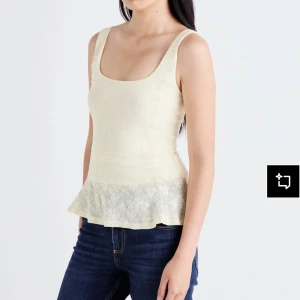 Krämvit spetslinne från Gina Tricot - Supersöt krämvit linnetopp från Gina Tricot med breda axelband och volangkant nertill. Toppen har ett diskret blommigt spetsmönster och är figurnära med lätt utsvängd nederdel. Perfekt för en fräsch och romantisk look. Helt ny