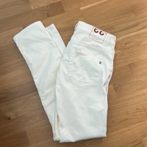 Dondup George  - Säljer ett par fräscha vita skinny jeans från Dondup. Byxorna har klassisk femficksdesign, smal passform och är tillverkade i bomull. Perfekta för dig som gillar stilrena och ljusa jeans med modern look. Jeansen är i väldigt fint skick, parfekta nu till sommaren eller vid festligheter