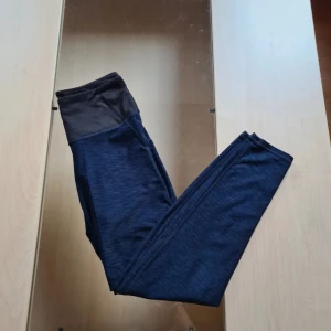 Mörkblå träningsbyxor  - Snygga mörkblå leggings från H&M med bred svart hög midja. Stretchigt material som sitter tight och bekvämt, perfekta för träning eller chill. Materialet är mjukt och följsamt, och färgen är diskret melerad blå med svart kontrast upptill.