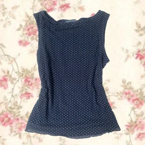 Mörkblå prickig topp Brandy Melville - Supersöt mörkblå ärmlös topp från Brandy Melville med vita små prickar över hela. Toppen har en lätt figursydd passform och rund halsringning.  ALDRIG ANVÄNT, den passar inte mig därför jag säljer💕💕