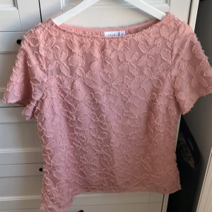 Rosa blommig blus från VILA - Säljer en söt rosa blus från VILA i storlek 38. Blusen har korta ärmar och är täckt av ett blommigt strukturmönster som ger en romantisk känsla. Perfekt att styla med jeans eller kjol för en fräsch look!