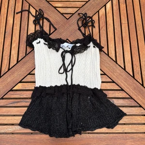 Svart och vit stickad linnetopp från Zara - Supersöt stickad linnetopp från Zara i svart och vitt. Toppen har knytband på axlarna, volangdetaljer och spets längs urringningen som inte går att köpa längre. Aldrig använd💕om man har frågor är det bara att skriva 🥰