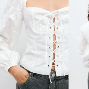 Vit broderad blus med snörning - Superfin vit blus med broderade detaljer och snörning framtill. Blusen har långa puffärmar och en fyrkantig urringning. Perfekt att styla med jeans för en trendig look. Köpt för 500kr!