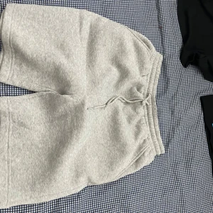 Grå mjukisshorts med snörning - Säljer ett par grå mjukisshorts med elastisk midja och snörning. Shortsen har en avslappnad passform och är tillverkade i mjukt material, perfekta för chill eller träning.