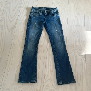 Blå bootcut jeans från Ltb - Snygga blå bootcut jeans från Ltb med slitna detaljer. Dme är i modellen Valerie. På ena fickan så har det blivit en liten rivning. Annars helt som nyskick. Dem är i storlek 24/30 men stretchiga. Rakt över är 36 cm.  Dessa är köpta för 1065 kr.