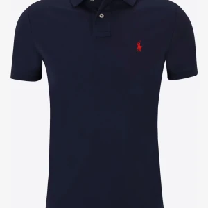 Mörkblå pikétröja från Ralph Lauren - Klassisk mörkblå pikétröja från Ralph Lauren med korta ärmar och röd broderad logga på bröstet. Tröjan har krage och knappar vid halsen. Perfekt för en stilren och avslappnad look.