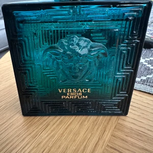 Versace Eros Parfum 100ml + Deostick - Säljer en lyxig Versace Eros Parfum 100ml i blå glasflaska med guldiga detaljer och Medusa-huvud samt matchande parfymdeostick. Doften är intensiv och maskulin, perfekt för dig som vill sticka ut med en ikonisk signaturdoft.