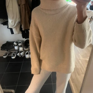 Beige stickad polotröja - Mysig beige stickad polotröja med lång ärm och bred polokrage. Tröjan har en avslappnad passform och ribbade muddar vid ärmslut och nederkant. Perfekt för kyliga dagar på sommaren med en fin kjol eller med ett par jeans!❤️‍🔥❤️‍🔥