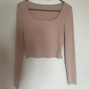 Beige ribbad croppad topp - Säljer en beige ribbad croppad topp med lång ärm och fyrkantig ringning. Perfekt att styla med jeans eller kjol för en enkel och trendig look.🤎