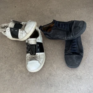 Svarta och vita sneakers med tejpdetalj - Två par sneakers, ett par i svart och ett par i vitt med svart tejpdetalj över snörningen. Klassisk rund tå och platt sula. Perfekta för en avslappnad streetstil.