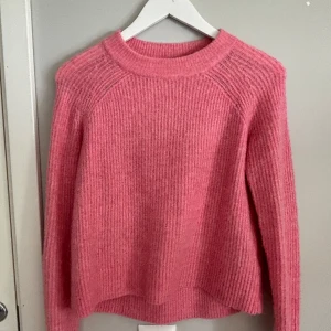 Rosa stickad tröja från H&M - Mysig rosa stickad tröja från H&M Basic-kollektionen. Tröjan har rund halsringning och långa ärmar med ribbad struktur. Perfekt för lager-på-lager och enkel att matcha med olika outfits.