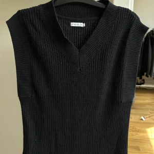 Svart stickad väst från STOCKH LM - Snygg svart stickad väst från STOCKH LM med v-ringad halsringning. Västen har en grovstickad struktur och är ärmlös, perfekt att styla över en skjorta eller t-shirt. Storlek S men den är lite oversized.