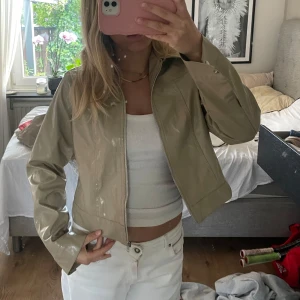 Beige glansig jacka med dragkedja - Säljer en beige, glansig jacka med dragkedja framtill. Helt ny med lappen kvar men säljer då jag inte fått användning för den😍