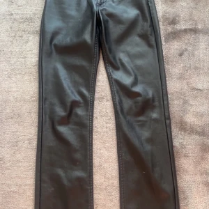 Svarta skinnbyxor från Bik Bok - Säljer ett par svarta skinnbyxor från Bik Bok med normal passform och raka ben. Byxorna har klassisk femficksdesign, knapp och dragkedja framtill. Perfekta för att lyfta vilken outfit som helst. Lite smått lurviga inuti, midjan är medel