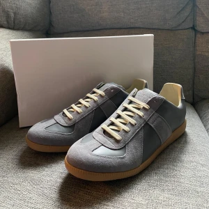 Grå Maison Margiela Gats | Strl 43 | Nyskick - Snygga grå sneakers med ljusgrå mockadetaljer och beige sula. Skorna har snörning och en klassisk, stilren design med rund tå. Perfekta för dig som gillar en clean och tidlös look.