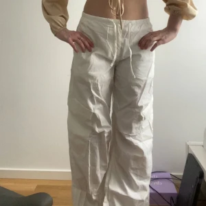 Vita parachute byxor (tall) - Säljer ett par vita byxor från Gina Tricot med bred passform och mid-waist. Byxorna är tillverkade i bomull och har en avslappnad, loose stil. Perfekta för en trendig och bekväm look. Modellen är tall och jag säljer dem eftersom de är lite för långa för mig (är 173). 