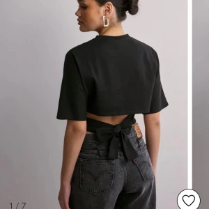 back tie topp - Snygg svart croppad topp med korta ärmar och en stor knytrosett i ryggen. Viral nelly topp som är helt ny och syperfin!!! Fick den i födelsedagspresent men den passade tyvärr inte mig❤️❤️