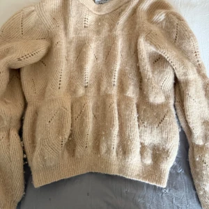 Beige stickad tröja från & Other Stories - Säljer en beige stickad tröja från & Other Stories Paris Atelier. Tröjan har ett snyggt mönster med håldetaljer och är långärmad med ribbade muddar. Perfekt för lager-på-lager och passar till många olika stilar. Köpt för 1500