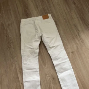Vita slim jeans från Jack & Jones - Snygga vita jeans från Jack & Jones i modellen SLIM/GLENN. Byxorna har klassisk femficksdesign, dragkedjegylf och smal passform. Perfekta för dig som gillar en clean och fräsch look. Materialet är mjukt och stretchigt för extra komfort.
