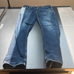 Levi's 512 Slim Taper jeans blå Storlek: 16A OBS små i storlekarna  - Säljer ett par Levi's 512 Slim Taper jeans i klassisk blå denim. Jeansen har smal passform med avsmalnande ben, snygga slitningar och kontrastsömmar. Perfekta för dig som gillar en modern men tidlös look. Lite använda och ett jack i högra knäet på byxorna 