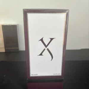 Parfym Xerjoff 100 ml - Lyxig parfym från Xerjoff i en elegant mörklila kartong med vit och guld detalj på framsidan. Flaskan rymmer 100 ml och är perfekt för dig som gillar exklusiva dofter och snygg design.