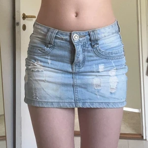 Vintage Ljusblå jeanskjol  - Säljer en ljusblå, kort jeanskjol från Miss Anna med slitna detaljer och klassiska fickor både fram och bak. Kjolen har bälteshällor, knapp och dragkedja framtill. Supersöt till sommaren. Har en liten missfärgning men den syns knappt enligt mig. 