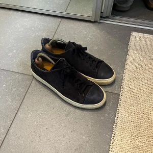 Svarta sneakers från Sneaky Steve - Svarta sneakers från Sneaky Steve med ovandel i mocka och tåparti i skinn. Skorna har snörning och en vit platt sula som ger en klassisk look. Perfekta för dig som gillar stilrena och tidlösa sneakers med en twist.