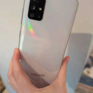 Begagnad telefon i mycket gott skick  - Det här är ingen bok, utan en Samsung-smartphone. Bilderna visar både fram- och baksidan av mobilen, inklusive startskärmen. Finns en spricka från ena kanten till ungefär till mitten av långsidan. 