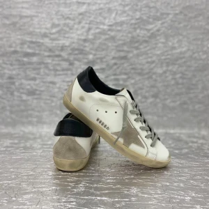 Golden Goose Superstar sneakers vit/grå - Golden Goose Superstar sneakers i vitt skinn med grå stjärndetalj på sidan, grå snörning och svart hälparti. Snyggt slitna detaljer och platt sula ger en cool och avslappnad vibe. Perfekta för dig som gillar streetstyle och italiensk design. 12-15 dagar leveranstid.