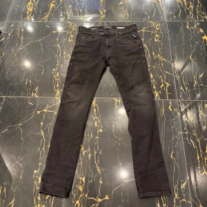 Svarta Replay Hyperflex Anbass jeans - Säljer ett par svarta Replay Hyperflex Anbass jeans med slim passform . Jeansen har klassisk femficksdesign, dragkedja och knapp i midjan samt diskret Replay-logga på fickan. Storleken är W31/L32 (pris kan diskuteras vid snabb affär 