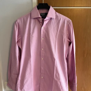 Ljusrosa skjorta från Polo Ralph Lauren - Säljer en klassisk ljusrosa skjorta från Polo Ralph Lauren, modell Regent Classic Fit. Skjortan har lång ärm, knappar framtill och klassisk krage. Perfekt för dig som gillar stilrena och tidlösa plagg.