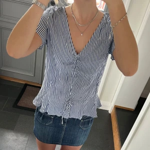 Blå randig topp  - Blå/vit randig topp med volanger och snörning från H&M i storlek 36. Nyskick, lappen kvar. Använd gärna köp nu!