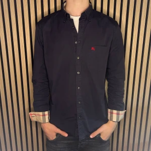 Burberry skjorta marinblå  - Marinblå burberry skjorta. Skick 8,5/10. Skjortans färg har blivit en aning sliten. Hör gärna av dig vid minsta fundering😊Och besök gärna min profil för liknande. 