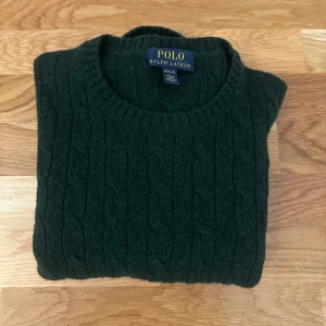 Mörkgrön kabelstickad tröja från Polo Ralph Lauren - En mörkgrön kabelstickad tröja från Ralph lauren. Den är i storlek M(10-12), barnstorlek. Den är köpt på NK för några år sedan.