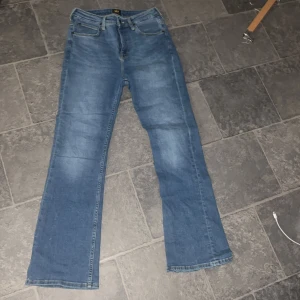Lee Breese Bootcut Jeans - Säljer ett par klassiska blå bootcut jeans från Lee, modell Breese Boot. Jeansen har fyra fickor, normal passform och snyggt Lee-märke baktill. Perfekta för dig som gillar en tidlös denimlook med lite utsvängda ben.