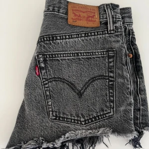 Grå jeansshorts från Levi's med fransar - Säljer ett par grå jeansshorts från Levi's med fransar nertill och klassiska bakfickor. De är relativt lågmidjade💕 Står ingen storlek i men passar S/XS