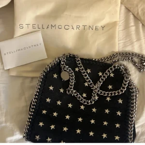 Stella McCartney svart axelväska med stjärnor - Super snygg stella mc väska som jag haft ett långt tag nu, är inte 100% på om den är äkta men tror det (därav pris), super skick förutom att en stjärna på utsidan saknas. Kort och dustbag följs med. Skicka gärna prisförslag!
