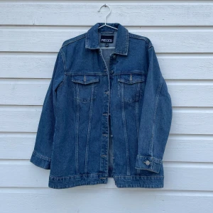 Blå jeansjacka från Pieces - Snygg blå jeansjacka från Pieces i storlek XS. Jackan har en klassisk design med knappar framtill och två bröstfickor. Perfekt för en avslappnad stil.
