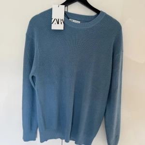 Blå stickad tröja från Zara - Säljer en stilren blå stickad tröja från Zara. Tröjan har rund halsringning och långa ärmar. Perfekt för lager-på-lager och enkel att matcha med olika outfits.